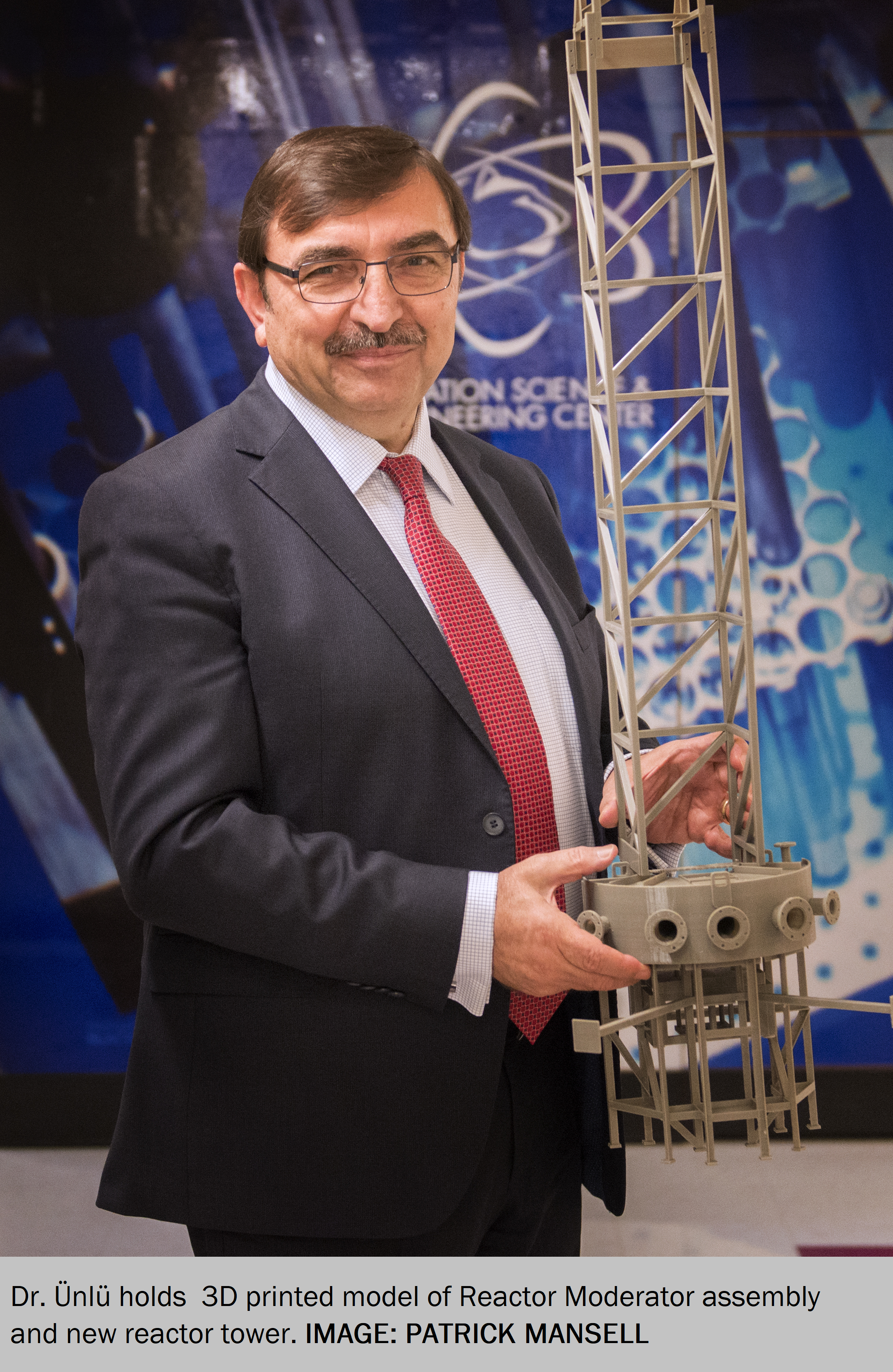 Dr. Unlu stands with a model of the new heavy water reflector